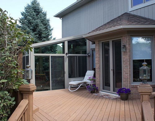 An upper deck with a sunroom in the rear and a patio entrance to the right. 