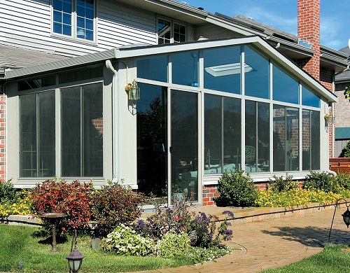 A sunroom with floor-to-ceiling glass walls and a peaked roof. 