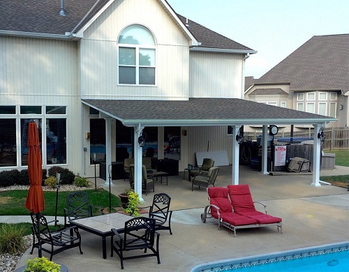 A covered patio. outdoor sitting area and poolside lounge chairs in the backyard of a typical suburban home. 